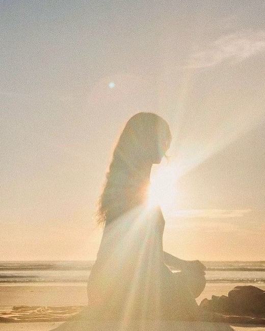 Woman sitting on a beach at sunset